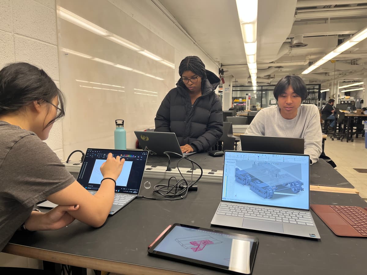 Four team members working on laptops and a tablet, with locomotive CAD open on one screen.